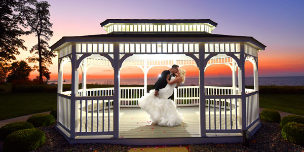 A bride and groom kiss at sunset in a gazebo overlooking Lake Erie at The Lodge at Geneva-on-the-Lake